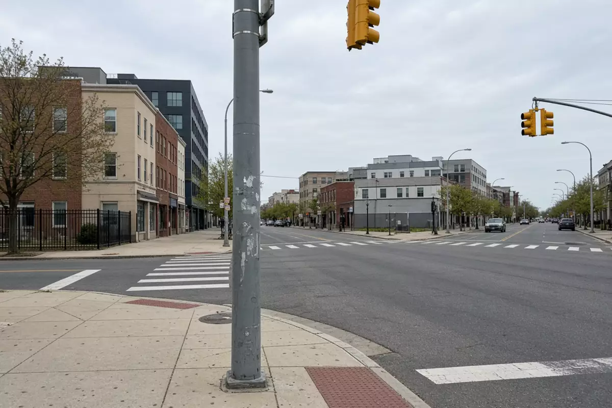 An ordinary city intersection with a roadside pole and traffic signals.